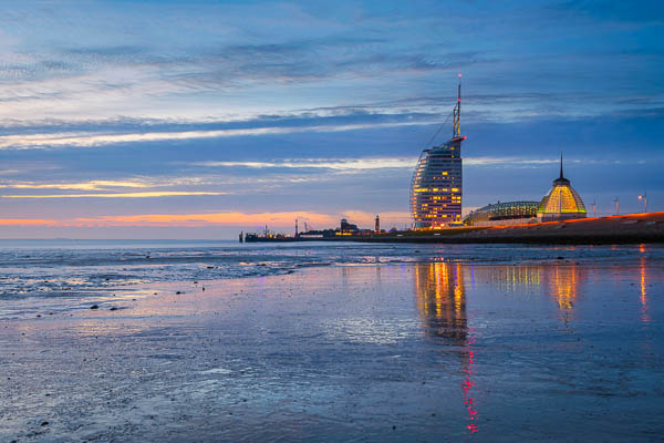 Weserufer bei Nacht in Bremerhaven, Deutschland, mit dem Atlantic Hotel Sail City im Hintergrund, gespiegelt im Watt bei Ebbe von Michael Abid