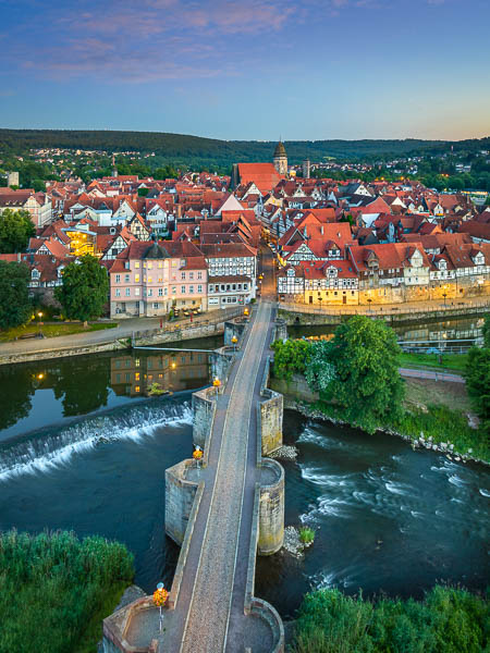 Nächtliche Luftaufnahme der historischen Altstadt von Hannoversch Münden (Hann. Minden) in Niedersachsen, Deutschland, mit beleuchteten Fachwerkhäusern, der Werrabrücke und dem Werra-Fluss von Michael Abid