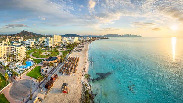 Aerial panoramic view of Cala Millor on Mallorca, Balearic Islands, featuring a golden sandy beach, crystal-clear turquoise Mediterranean waters and a beautiful sunrise, Spain by Michael Abid